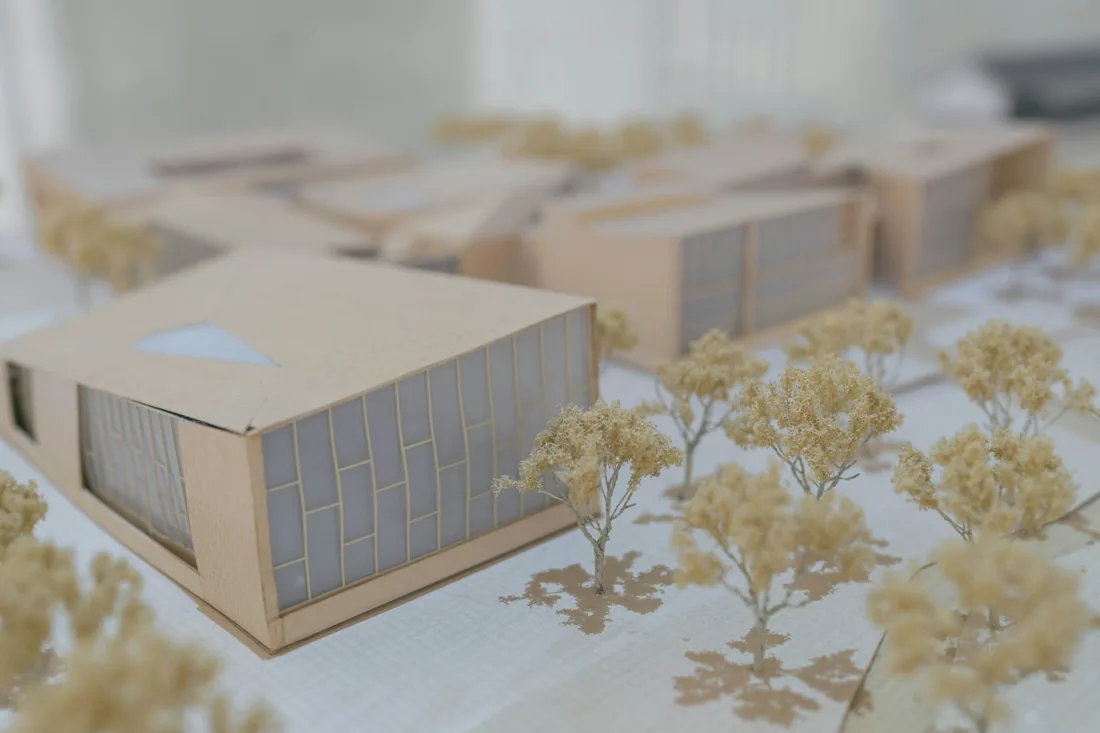 Architektonická maketa budovy z bílého a hnědého materiálu postavená na pracovní desce